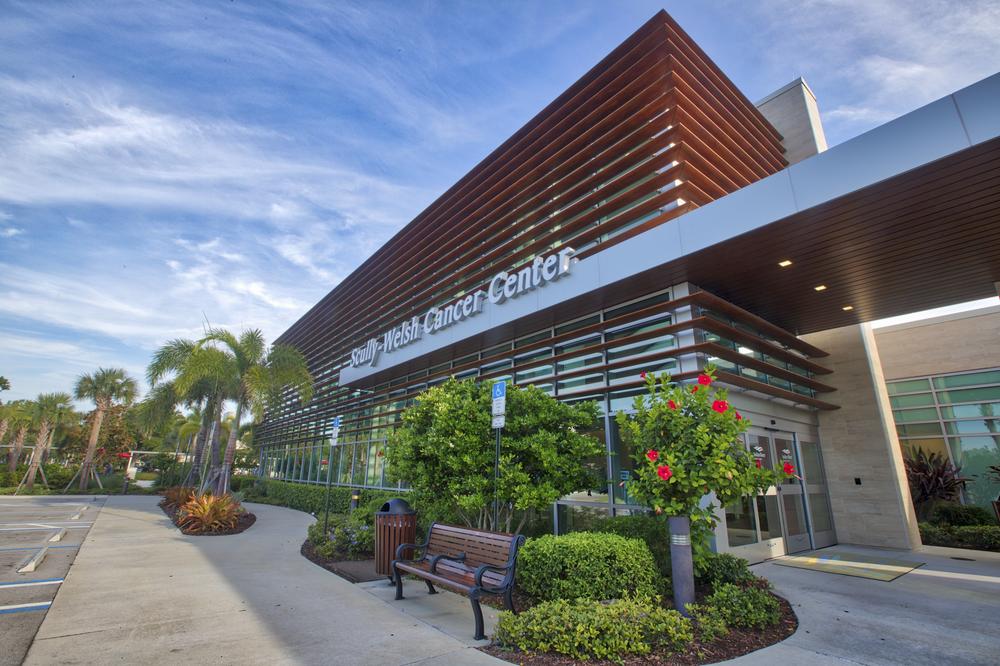 A shot of the Scully Welsh Cancer Center in Florida utilizing Nichiha’s VintageWood fiber cement siding in Cedar. There are palm trees around it, a lot of windows on the building and a large telescope sculpture propped in front.
