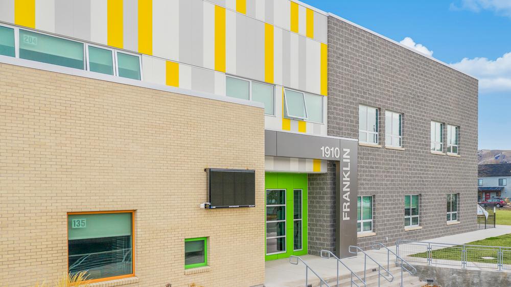 This school has yellow, white and gray fiber cement siding. There are steps leading to the front door.