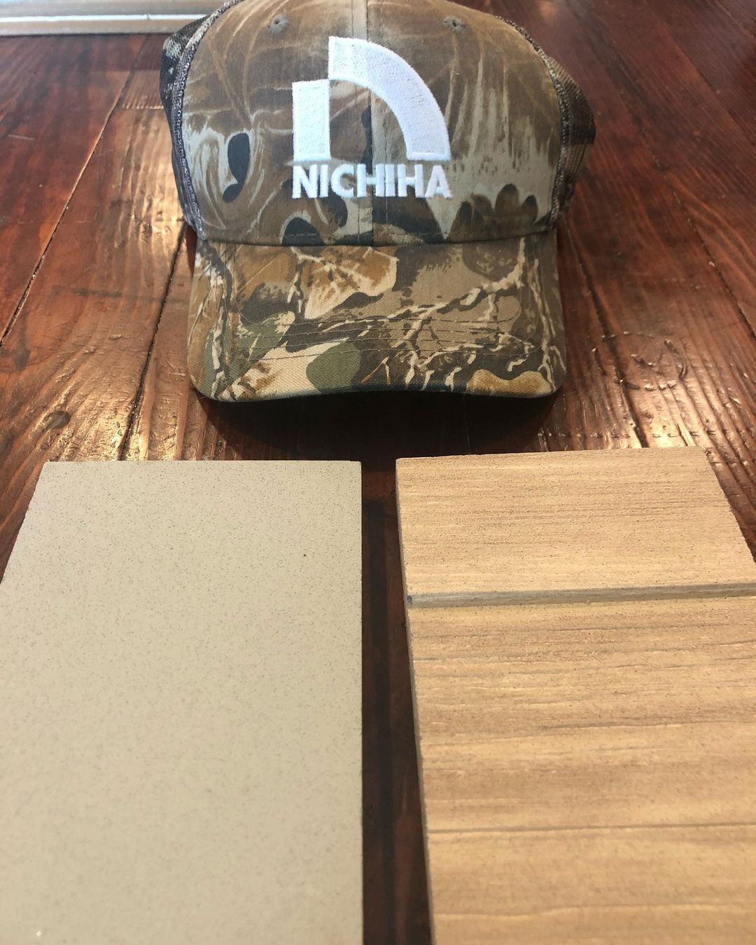 Samples of Nichiha fiber cement in VintageWood and ArchBlock in front of a camo hat with a Nichiha logo