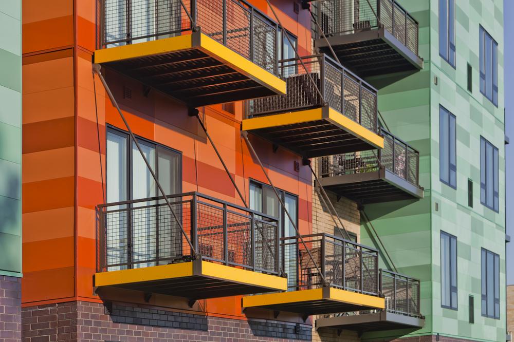 A close-up of Nichiha’s exterior fiber cement cladding on 444 Social multifamily units. The horizontal cladding panels are in custom shades of orange and green.