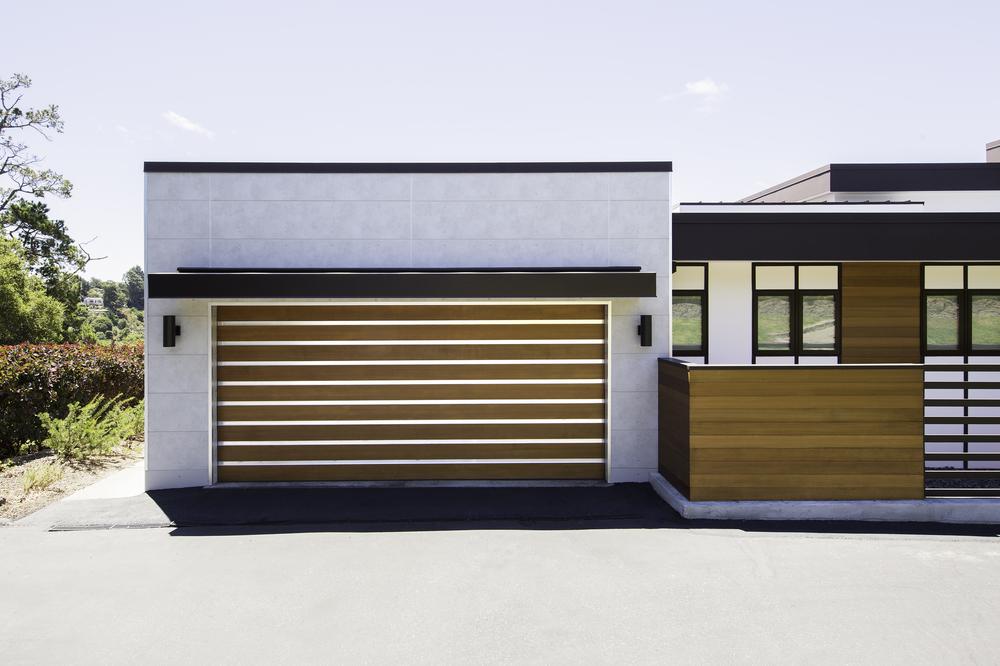 A modern home with white concrete and wood-accented exterior using fiber cement panels that create a linear and minimalist design.