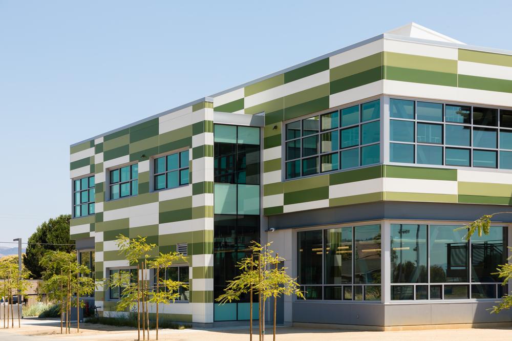 This commercial building uses various colored panels on the exterior. There are trees around the outside of the building. 