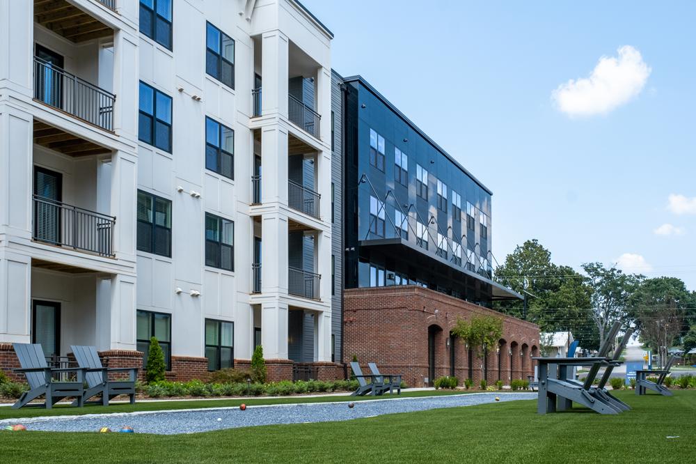 This apartment building has an outdoor area for games and lounging. There are balconies attached to the apartments. 