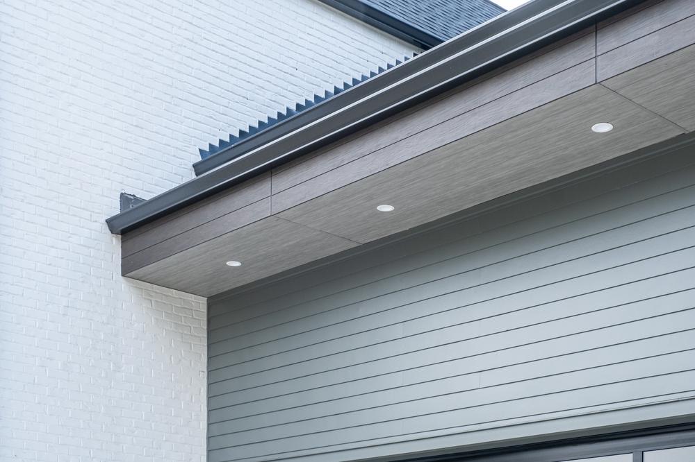 Exterior of home with wood-like soffit and outdoor recessed lighting.