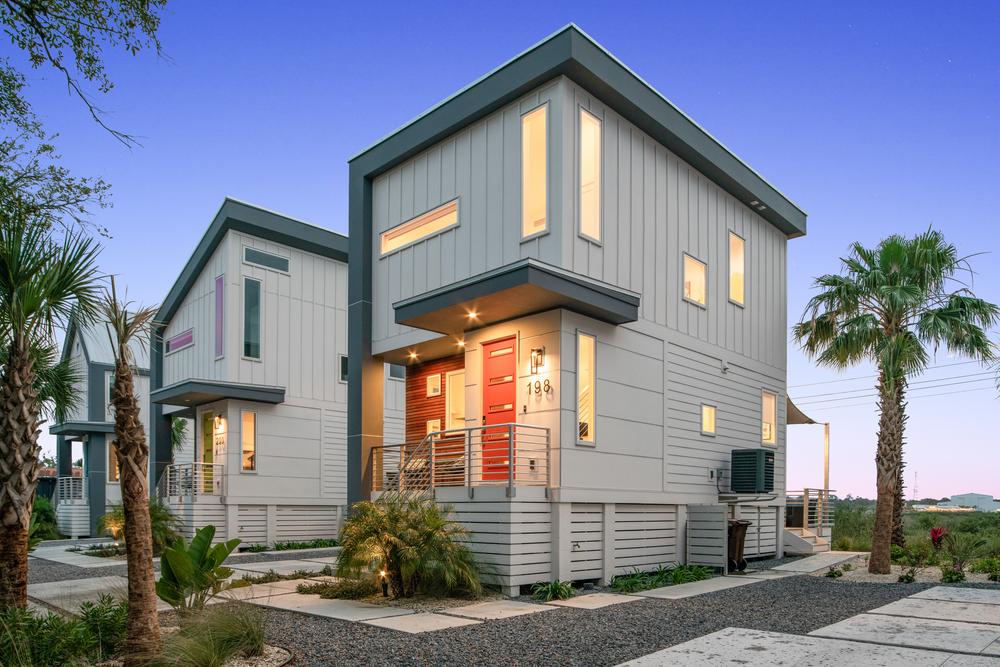 Modern house with a red front door. There are palm trees around the home.
