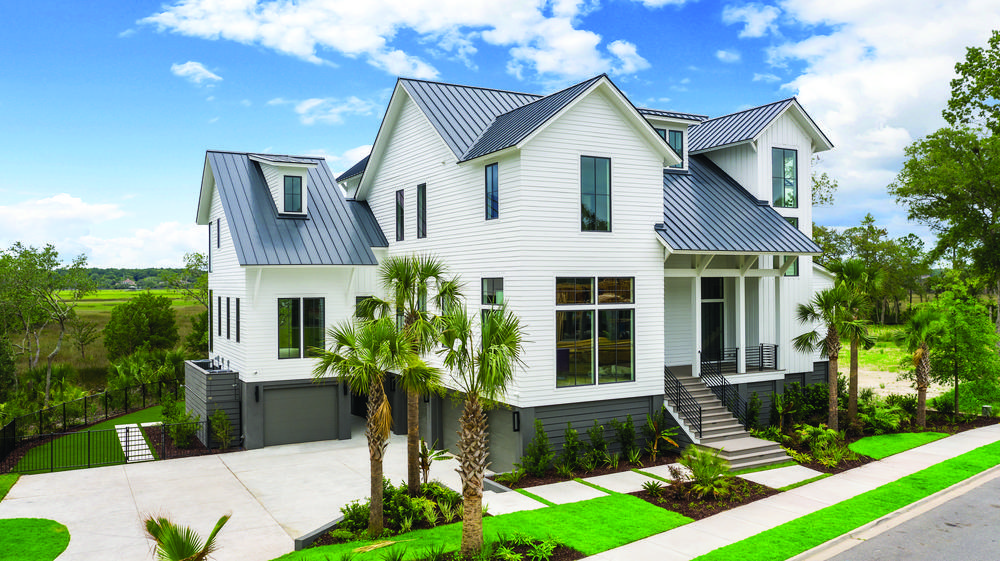 This white, two-story house with vibrant green lawn and palm trees overlooks the marsh.