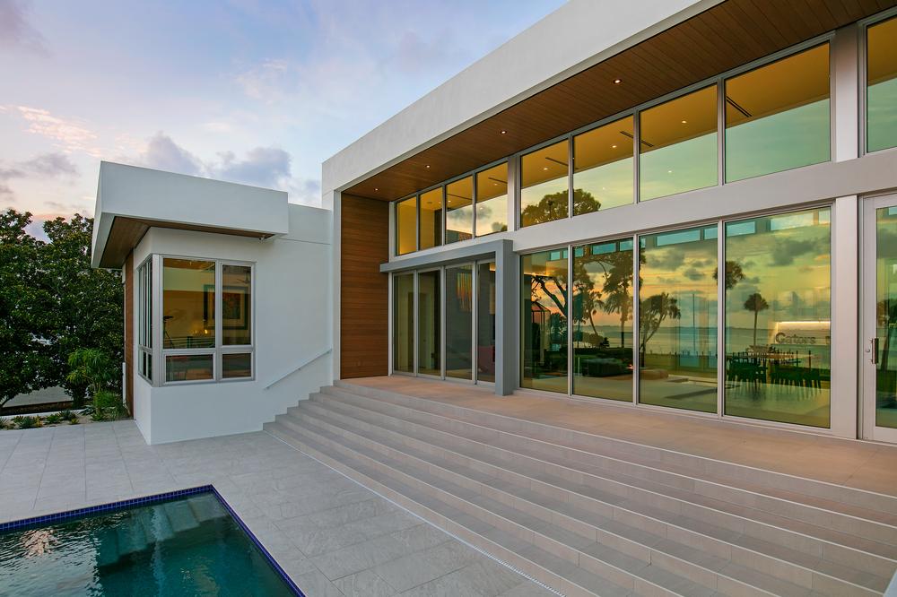 Modern exterior of the Osprey Landing Project. There is a pool and long steps leading up to the back of the structure.