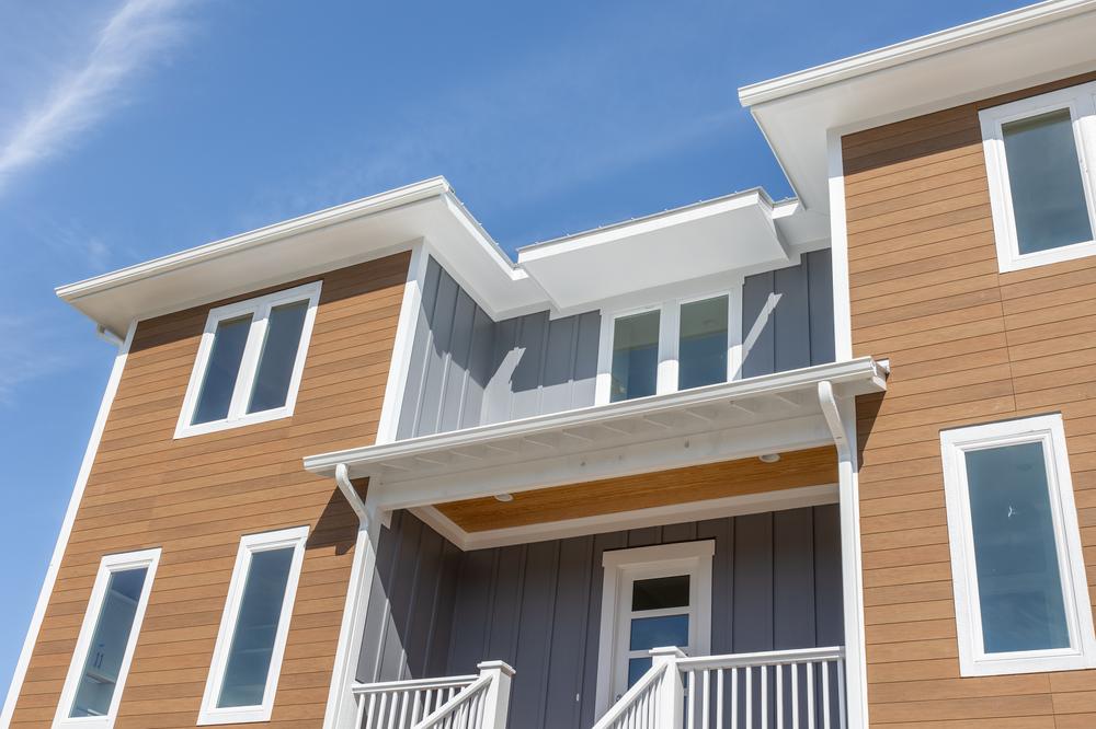 A two-story home with gray and brown siding and white trim.