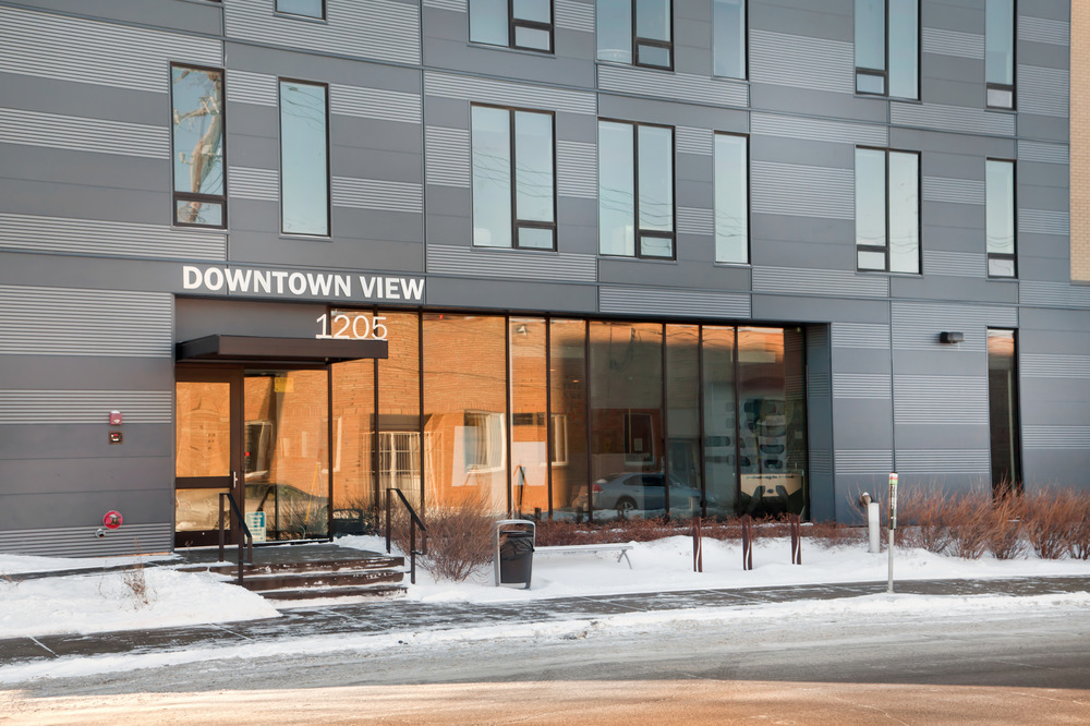 Entrance to an apartment building with white and gray mixed fiber cement siding.