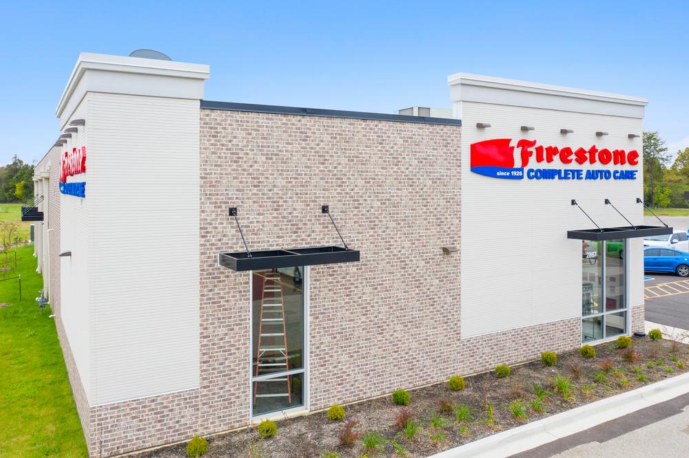 The front of Firestone Auto Care store with mixed colored brick siding and white fiber cement siding on the corners.