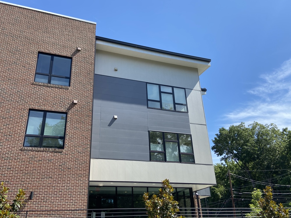 A multi-storied building with mixed brick and gray fiber cement siding.