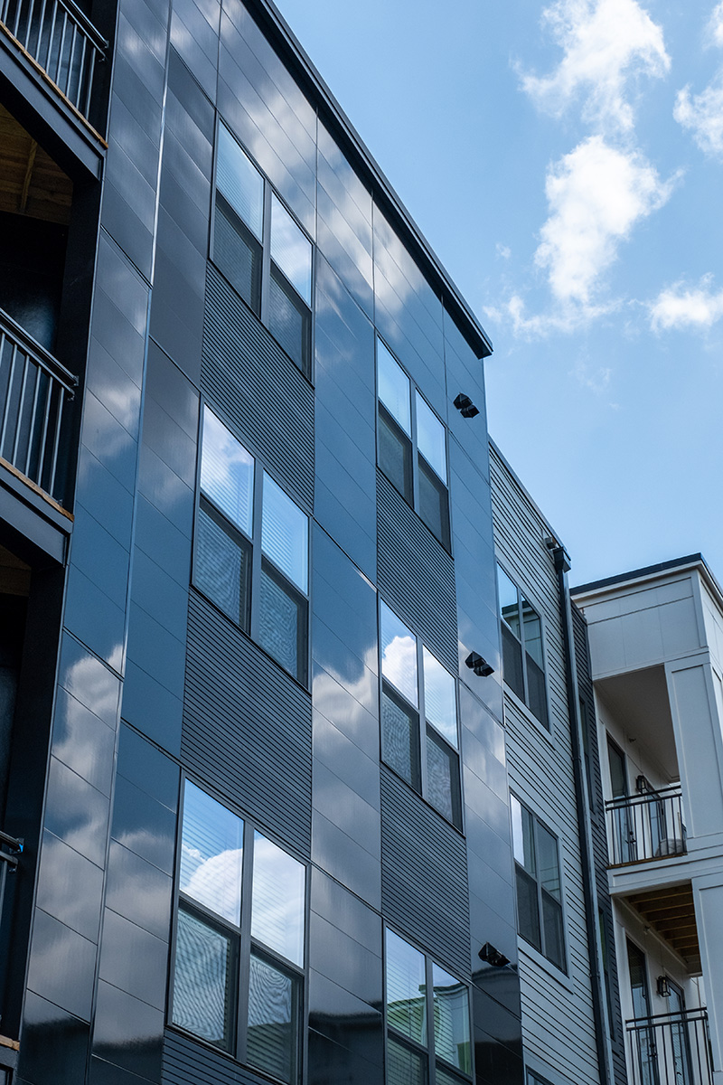 close up of Riverside multifamily building with clouds reflecting in the black miraia panels