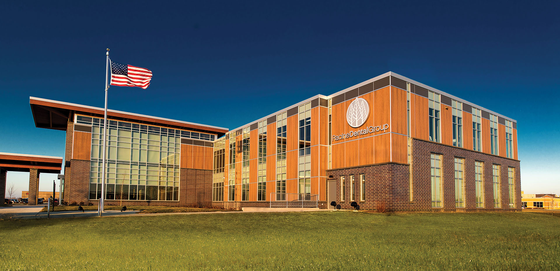 Exterior shot of Racine Dental with vertical VintageWood panels and an American flag flying