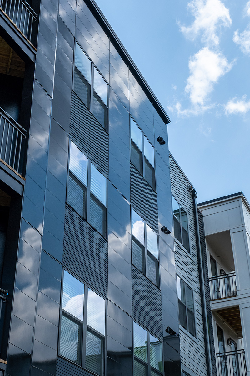 Looking up at the Riverside Multifamily complex with black Miraia fiber cement panels reflecting the clouds